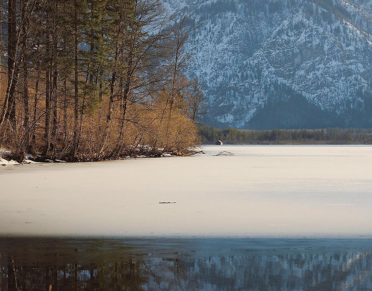 Uma mesa com mapas de lago nas montanhas, gráficos de espessura de gelo e cadernos de anotações abertos